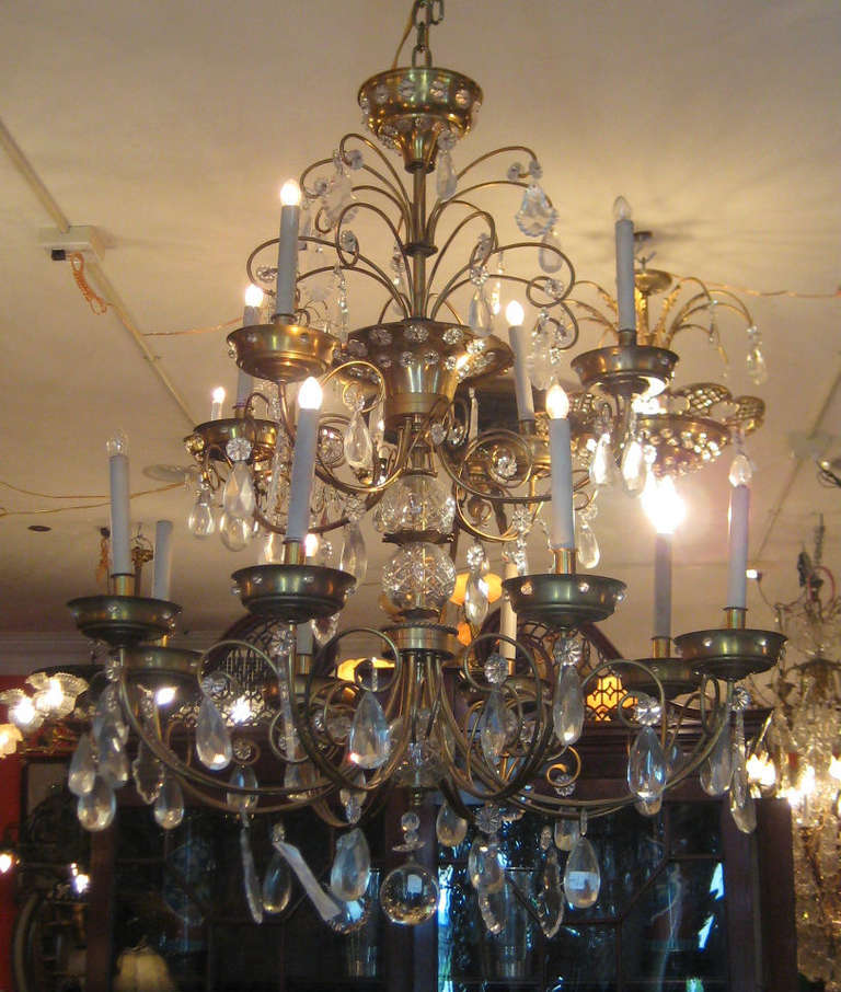 Maison Jansen bronze and crystal chandelier; the upper tier with four lights the lower tier with eight lights all hung with crystal pendalogs, rosettes and prismatic drops.