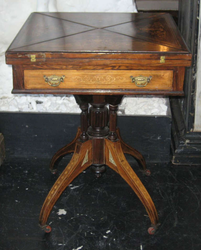 Regency inlaid rosewood handkerchief top pedestal game table, having a square four-fold inlaid handkerchief top over a single inlaid frieze drawer opening to a green felt playing card surface and four counter wells; the pedestal base with fluted