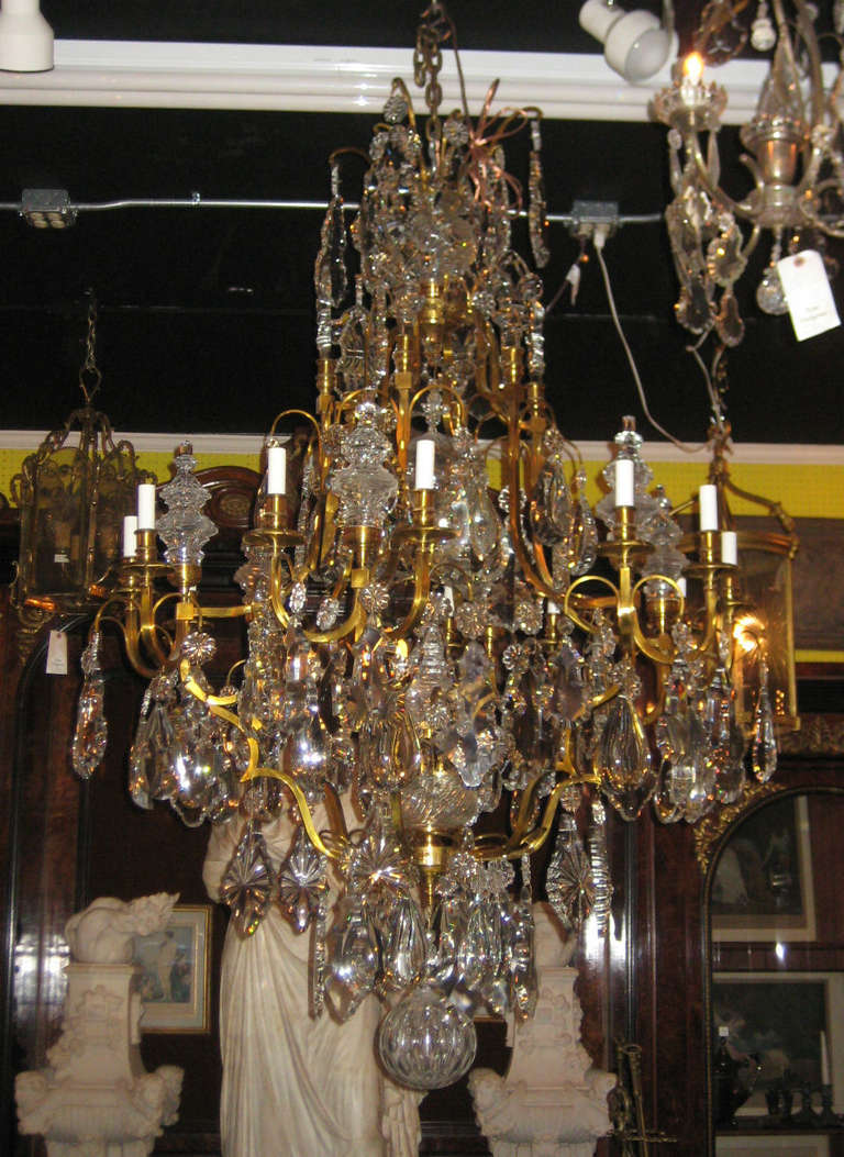 Large Louis XV twelve-light bronze and crystal chandelier hung with prismatic rosettes, tear drops, pendalogues, spires and fleur-dis-lys, termintating with a cut crystal ball.
