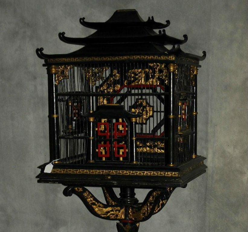 Chinese black and red lacquer and parcel-gilt birdcage (bird cage) on stand. The rectangular cage with pagoda top, two revolving feed doors, the interior back with carving, a fixed position swing-form perch, on a leaf shaped standard joining a