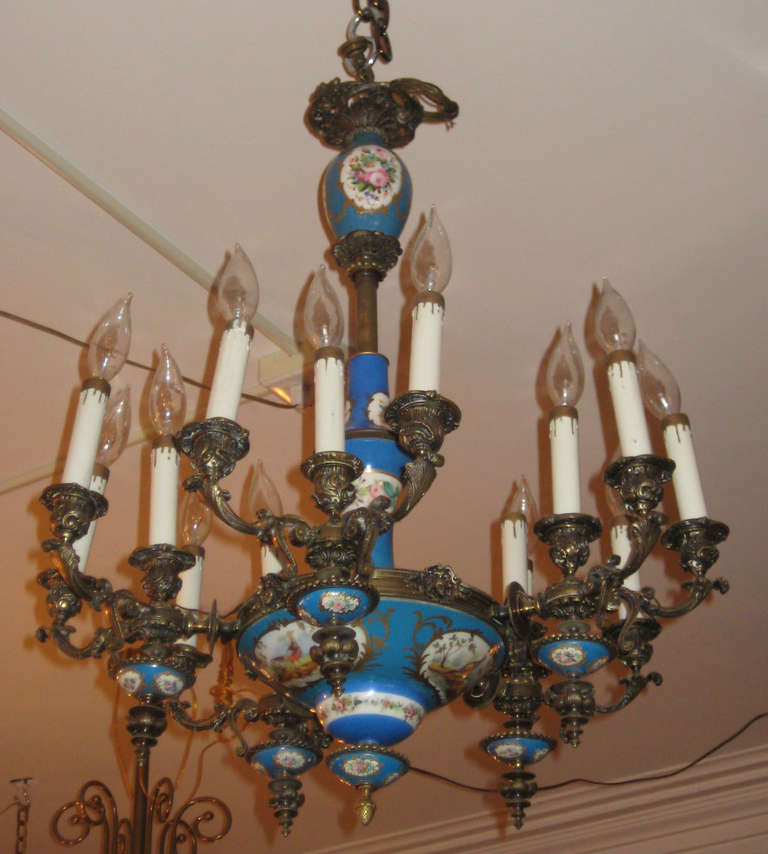 Sèvres porcelain and bronze fifteen-light chandelier, celeste blue porcelain decorated with floral and scenic bird cartouches, three lights to each of the five candle arms.

Note: The masks can be removed from around the chapter ring leaving only