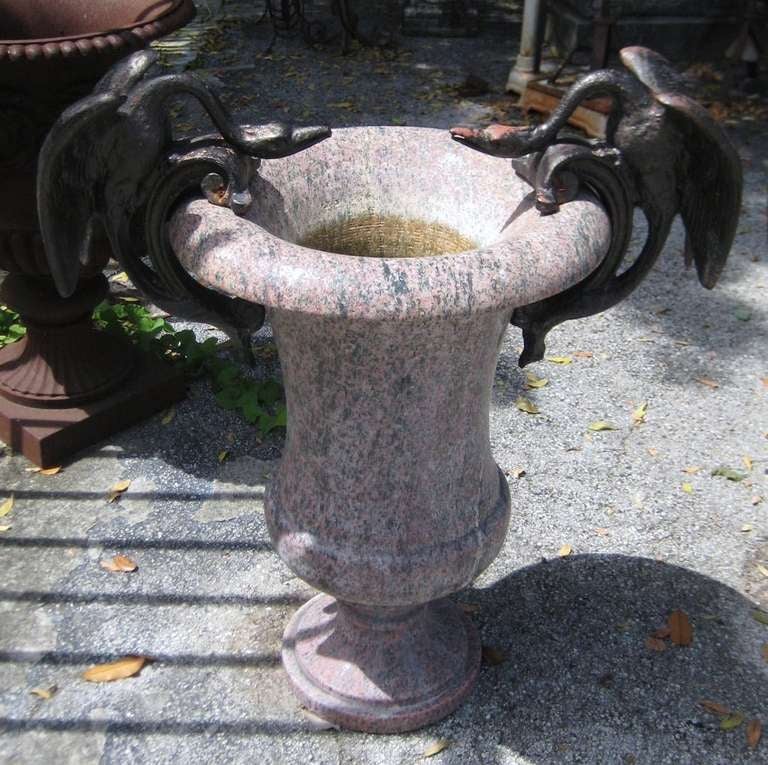 Large pair of carved granite urns with iron swan handles, pink and gray granite of inverted bell-form with applied iron swan-form handles. 

Measures: Height: 33 1/2