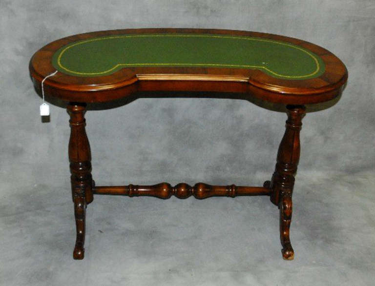 Regency mahogany kidney shape writing table with inset green tooled leather top above a turned and carved stretcher base.