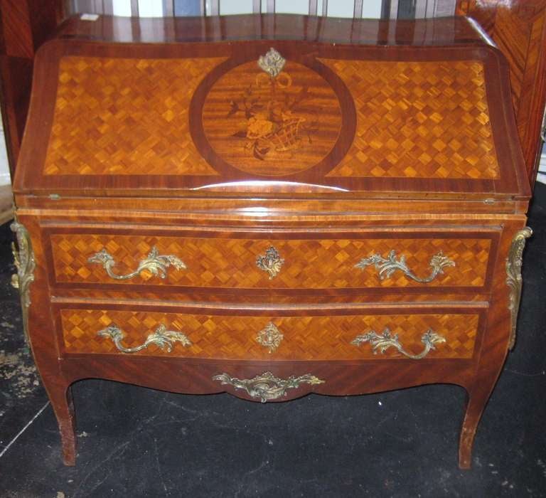 19th c. Louis XV style marquetry and parquetry inlaid bombe-form desk, having a slant front opening to reveal a fitted interior centering an open area flanked by four drawers and having a leather writing surface, all above two long drawers with