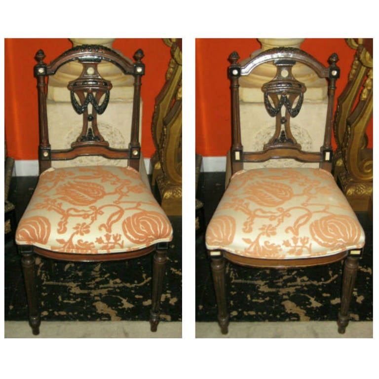 Four Edwardian carved mahogany and ebonized parlor or side chairs with mother-of-pearl inlay, carved crest rail with acorn finials, vasiform splat on circular tapering fluted legs ending on arrow foot.