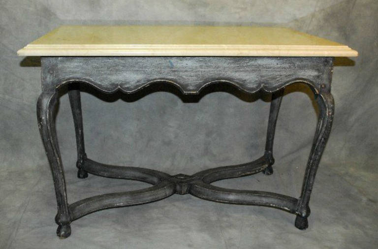 Provincial carved and painted center table, having a polished travertine marble molded edge top above a rectangular blue-grey painted table base with peg construction, scalloped apron on tapering cabriole legs with x-stretcher support.