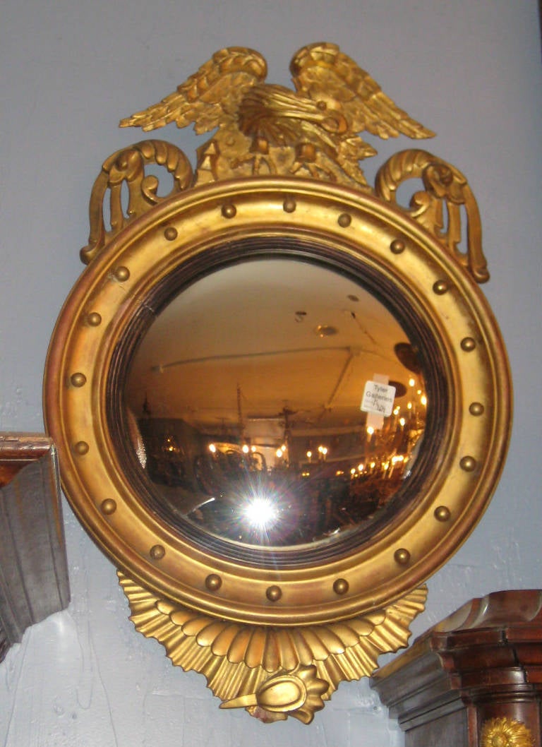 Federal carved gilt-wood carved convex glass bullseye mirror surmounted with a spread wing eagle.