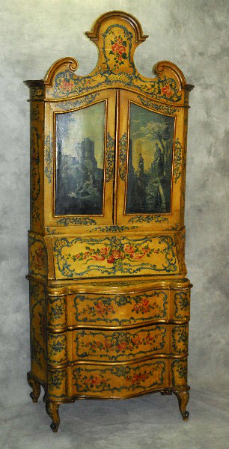 Beautiful 19th century Venetian painted two-part slant front secretary desk; the upper section with a shaped and molded cornice above a pair of en grisaille painted cabinet doors enclosing two shelves; the lower section with a slant front opening to