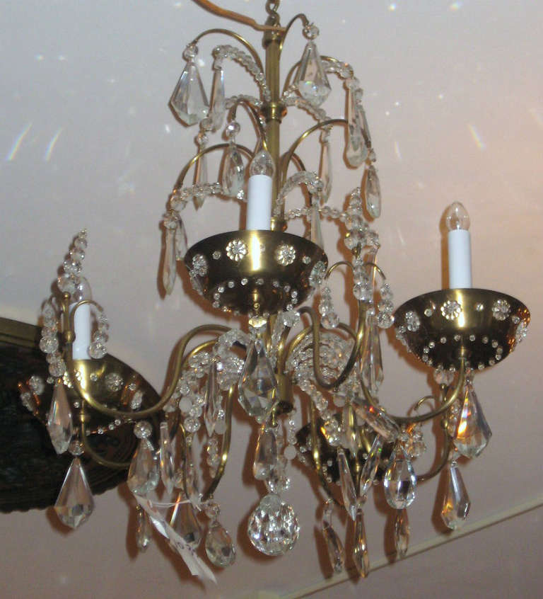 Maison Jansen Louis XV style bronze and crystal four-light chandelier. The bronze cage with four branches and bronze bobesches and hung with colorless rosettes, beads and pendalogues. 

[Maison Jansen - House of Jansen]