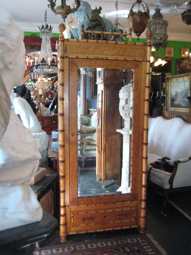 R. J. Horner maple and faux bamboo armoire, American circa 1890, Having a faux bamboo gallery cornice over beveled mirror door enclosing a shelved interior above a drawer, pilasters carved to simulate bamboo, panel sides with simulated bamboo