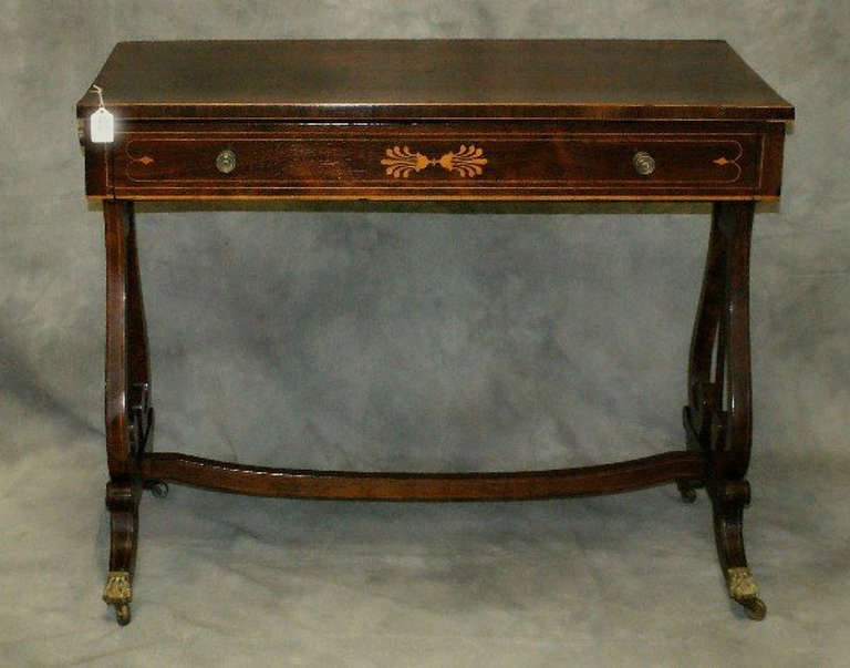 English Regency inlaid rosewood sofa table having a rectangular top above a single drawer, the sides with faux drawers raised on inlaid lyre form legs with brass rod strings joining a curved stretcher base.