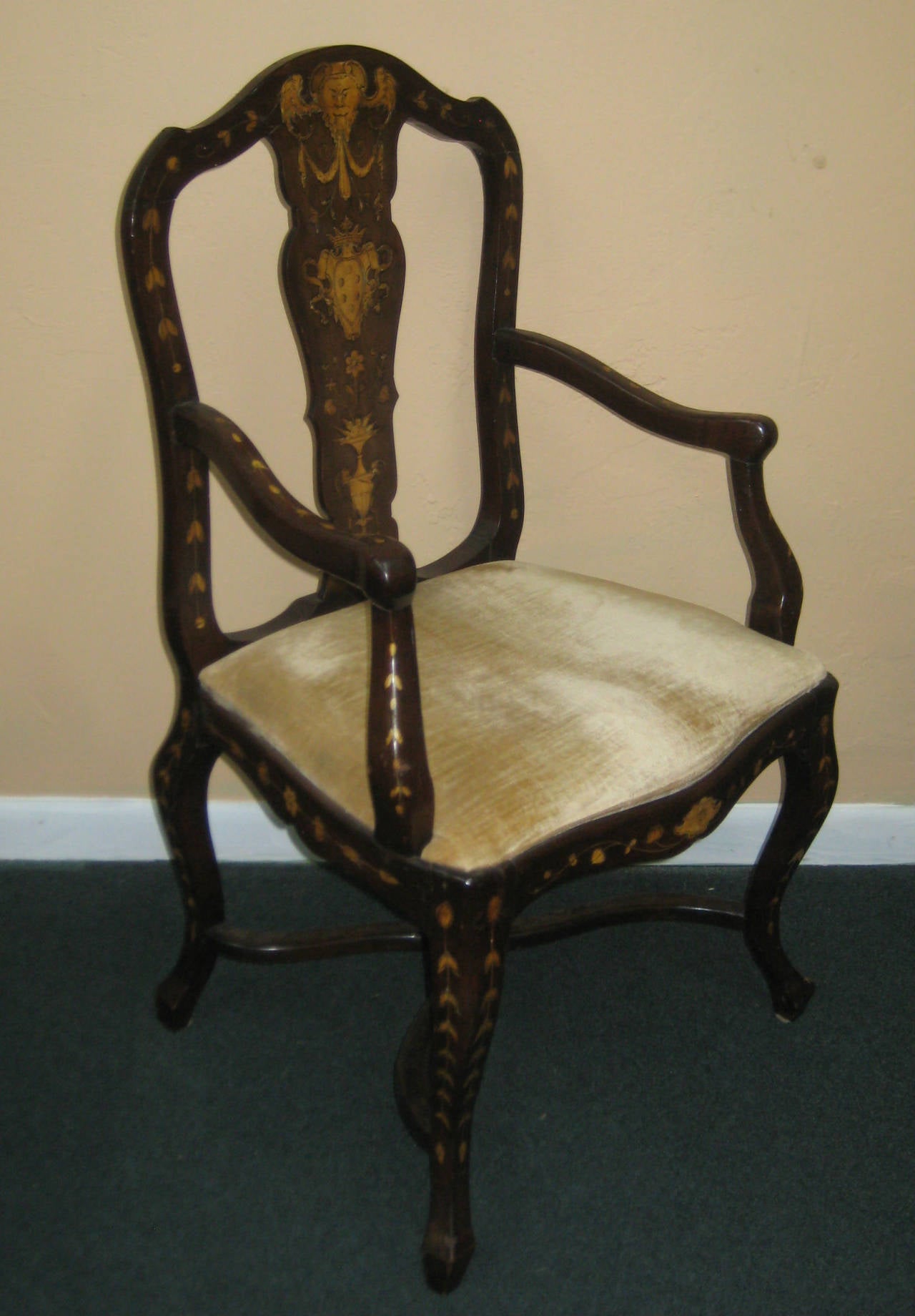 Dutch mahogany and marquetry armchair inlaid throughout with scrolling foliage, flowering basket, crest and mask, the arched top above a shaped splat and scroll arms, raised on cabriole legs.