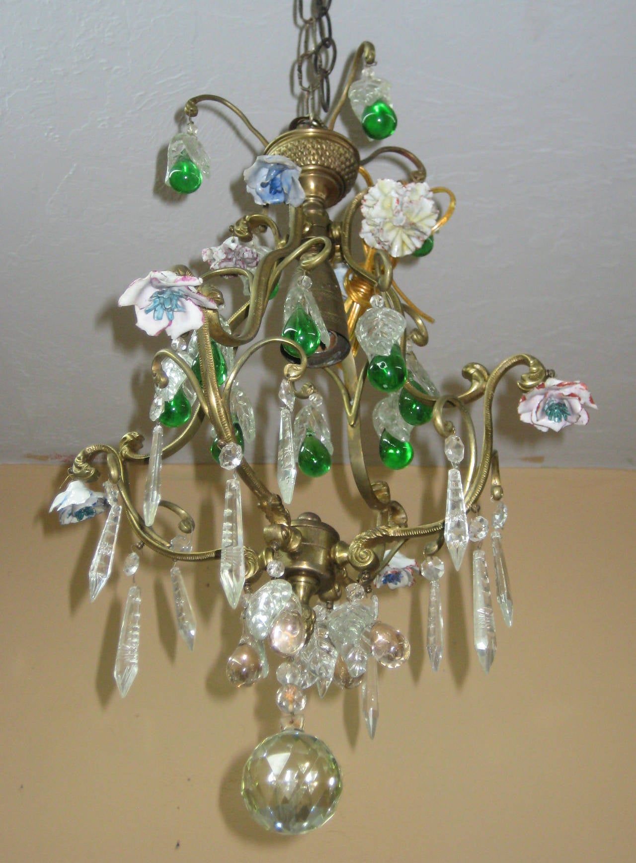 Fine bronze and crystal single light chandelier with color fruit and colorless leaves and porcelain flower heads.