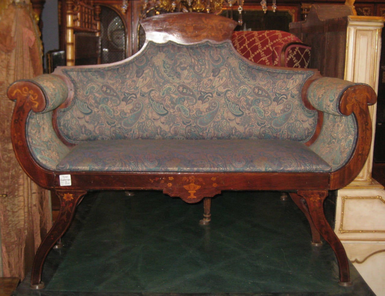 A beautiful inlaid mahogany settee, the shaped crest rail inlaid with a flowering urn flanked by birds and foliage above a shaped backrest, cornucopia shape arms inlaid with ribbons, flowerheads and trails, the seat rail centering a flowering urn