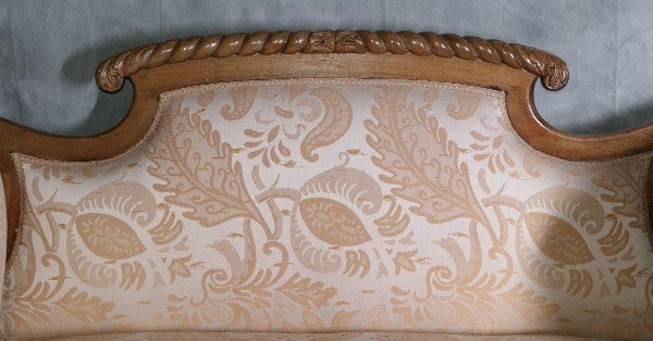 Empire carved mahogany settee, having a shaped back and scroll arms and garved seat rail continuing to winged legs ending with paw feet
