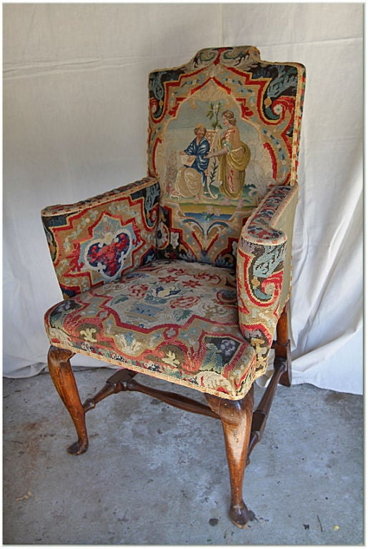 GEORGE I BEECHWOOD AND WALNUT NEEDLEWORK UPHOLSTERED ARMCHAIR UPHOLSTERED IN PETIT AND GROS POINT WITH FLORAL VINES AND A BIBLICAL SCENE DEPICTING ESTHER AND AHASUERUS. FIRST QUARTER 18TH CENTURY. THE CARVING ON THE INNER SIDE OF THE LEGS STAND OUT