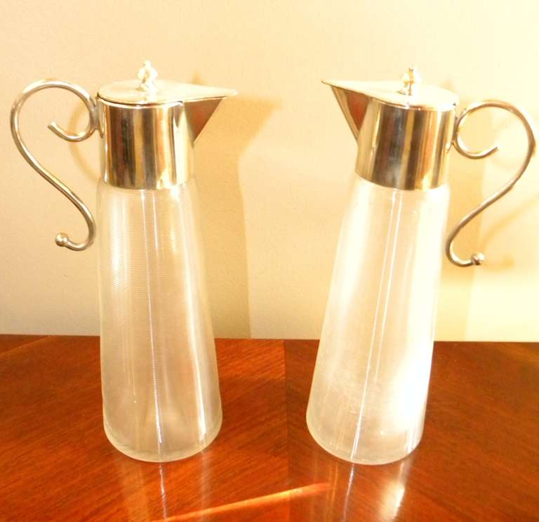 A stunning pair of modernist tableware carafes. Beautiful ribbed glass with nice silver-plate tops and extended handles: all fitted to work perfectly. These would be a useful addition to your home tableware set up. Simple and very elegant. Could be