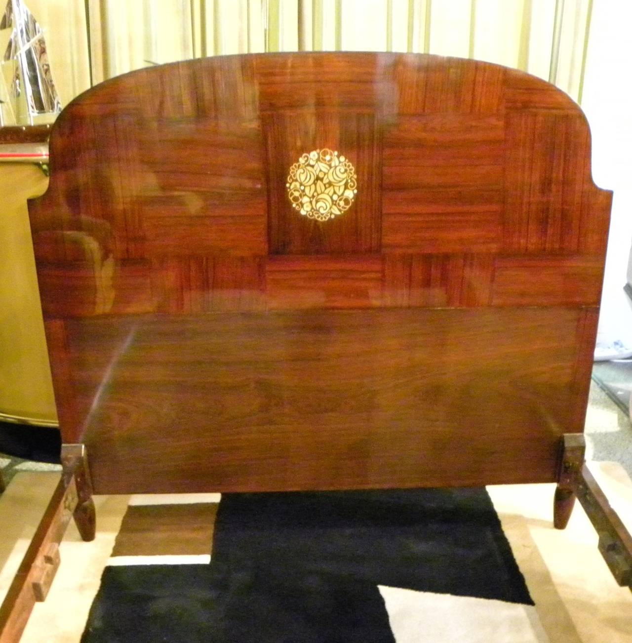 Detail and craftsmanship abound in this rich mahogany Art Deco bed frame with its wood grain laid out creating a unique checkerboard pattern. Both headboard and footboard depict a spectacular floral inlay work- a combination of mother-of-pearl,