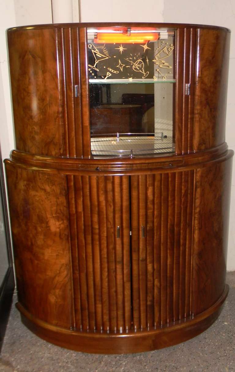 This 1930s Art Deco English Demi-Lune bar does a lot. It smartly and securely holds bottles, glasses, cocktail implements and accessories. It offers a first discreet then fun pull-out mixing shelf. It boasts a gorgeous walnut cabinet with