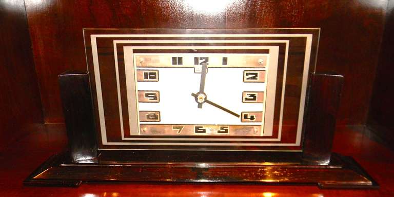 A handsome and refined Art Deco clock with varied textures and linear design. Made in Paris and signed by Leon Hatot - ATO. The metal and glass face slide into a stepped solid Rosewood base. The base has been recently refinished and the original
