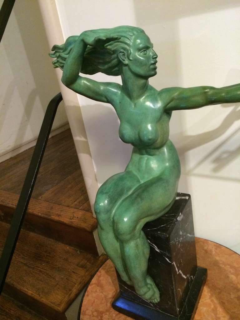 A powerful, dynamic and beautiful rendering of a woman in patina green with all the classic Art Deco details. She sits majestically on a black marble base, with the wind in her hair, and a bird in the hand. (and we all  know that