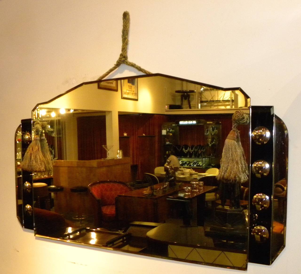 Beautiful Art Deco mirror with beveled edges, cut-out edges, circle designs and black glass. Original piece with original hanging period tasseled rope. Very dynamic style, would look great in a bathroom above a console or small piece of furniture.