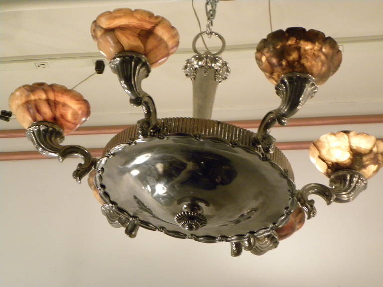 This unique combination of highly polished nickel with hand-carved alabaster is a good example of “ornate, early Art Deco.” Embellished with a motif of cascading grapes, fluted edging and scalloped cups of highly veined, warmly colored alabaster it
