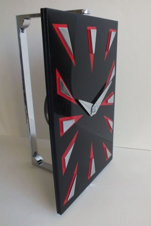 A very very rare English wall-mounted pivoting 8 day clock with a mirror finish red and black lacquer dial with chrome triangle markers and chrome hands. This stunning piece mounts in a heavy chrome frame that fixes to the wall. Very high quality