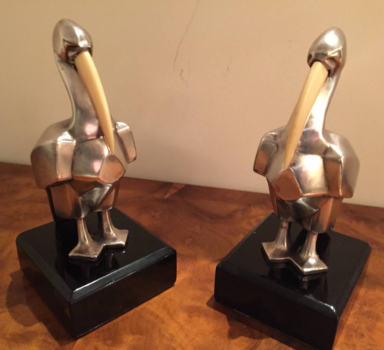 Unique cubist style Pelican bookends. Beautifully rendered with the stylized details of true art. This matching pair has been newly restored in silver. The elongated beaks seem to be an invorid material and lend an additional element to the overall