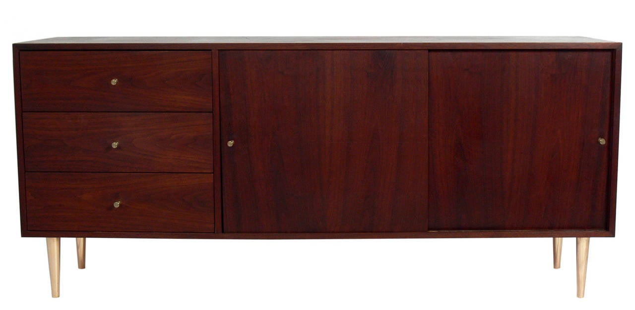 Walnut and Brass Credenza in the manner of Paul McCobb, American, circa 1950's. Beautiful graining to the walnut. This piece is a versatile size and can be used as a credenza, bar, or console in a living area, or as a dresser or chest in a bedroom.