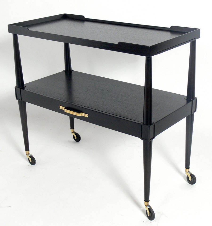Elegant Bar or Serving Cart, designed by Tommi Parzinger for Charak Modern, circa 1950's. It has been refinished in an ultra-deep brown lacquer and the brass hardware has been hand polished and lacquered. It measures 36