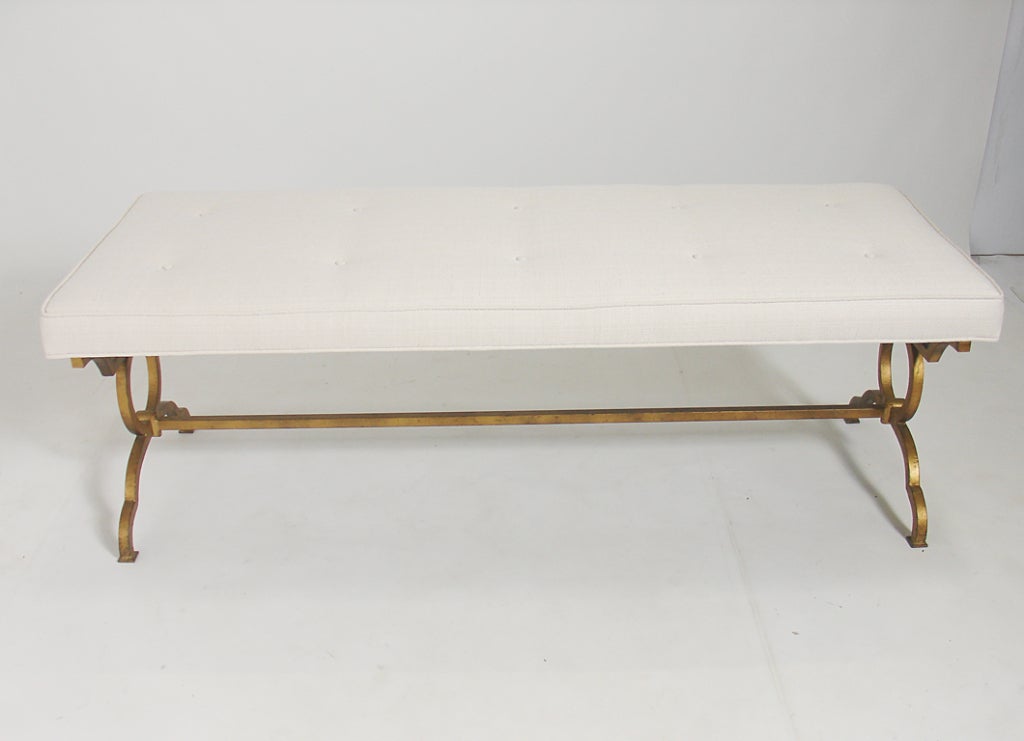 Neoclassical Gilt Bench, American, circa 1970's. It retains it's original painted gilt finish with a wonderful patina. Some overall wear to the metal frame, exposing the Chinese Red underlayer or bole. Reupholstered in an ivory color linen