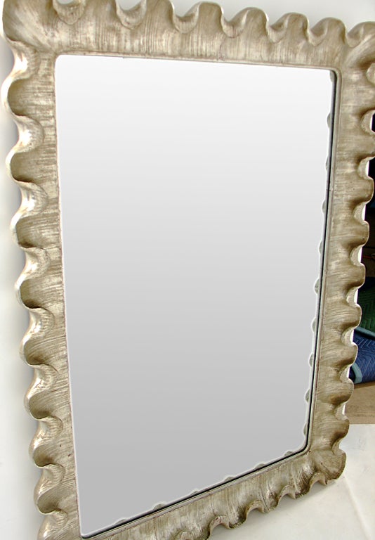 Venetian Scalloped Mirror, circa 1950's. Undulating curves of hand carved and gilt wood and plaster give this mirror it's elegant form. It exhibits wonderful patina and wear to the silver leafing, beautifully exposing some of the Chinese Red