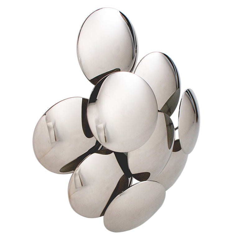 Pair of large scale sculptural chrome wall sconces or appliques, designed by Reggiani, circa 1970's. Wonderful mood lighting is emitted from the backlit discs, which cast sculptural shadows. Each sconce is mounted with a standard threaded electrical