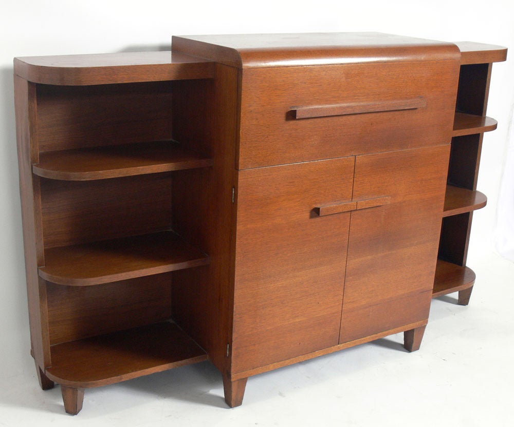 Selection of Art Deco Asymmetrical Bookcases / Credenzas / Drop Front Desks by Modernage, American, circa 1930's. They offer a voluminous amount of storage with numerous drawers, shelves and compartments. These pieces are currently being refinished
