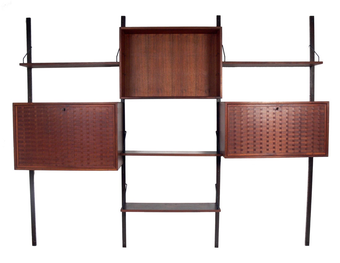 Danish Modern Wall Unit, designed by Poul Cadovius, Denmark, circa 1960's. This piece is completely adjustable, and any of the case pieces or shelves can be installed anywhere up and down the wall mounted uprights. 
This piece is a versatile size