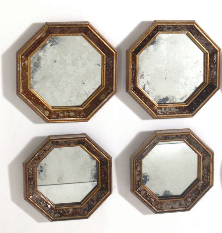 Two Groups of Antiqued Mirrors, American, circa 1950's. There is a group of four oval mirrors and a group of four octagonal mirrors. As each mirror is hand made, there are some slight size variations. There are two octagonal mirrors that are larger,