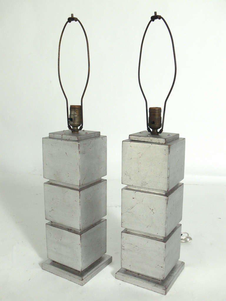 Pair of Silver Leaf Cube Lamps, American, circa 1940's. They exhibit wonderful patina and wear to the silver leafing, beautifully exposing some of the Chinese Red underlayer or bole. They retain their original finials, which echo the form of the