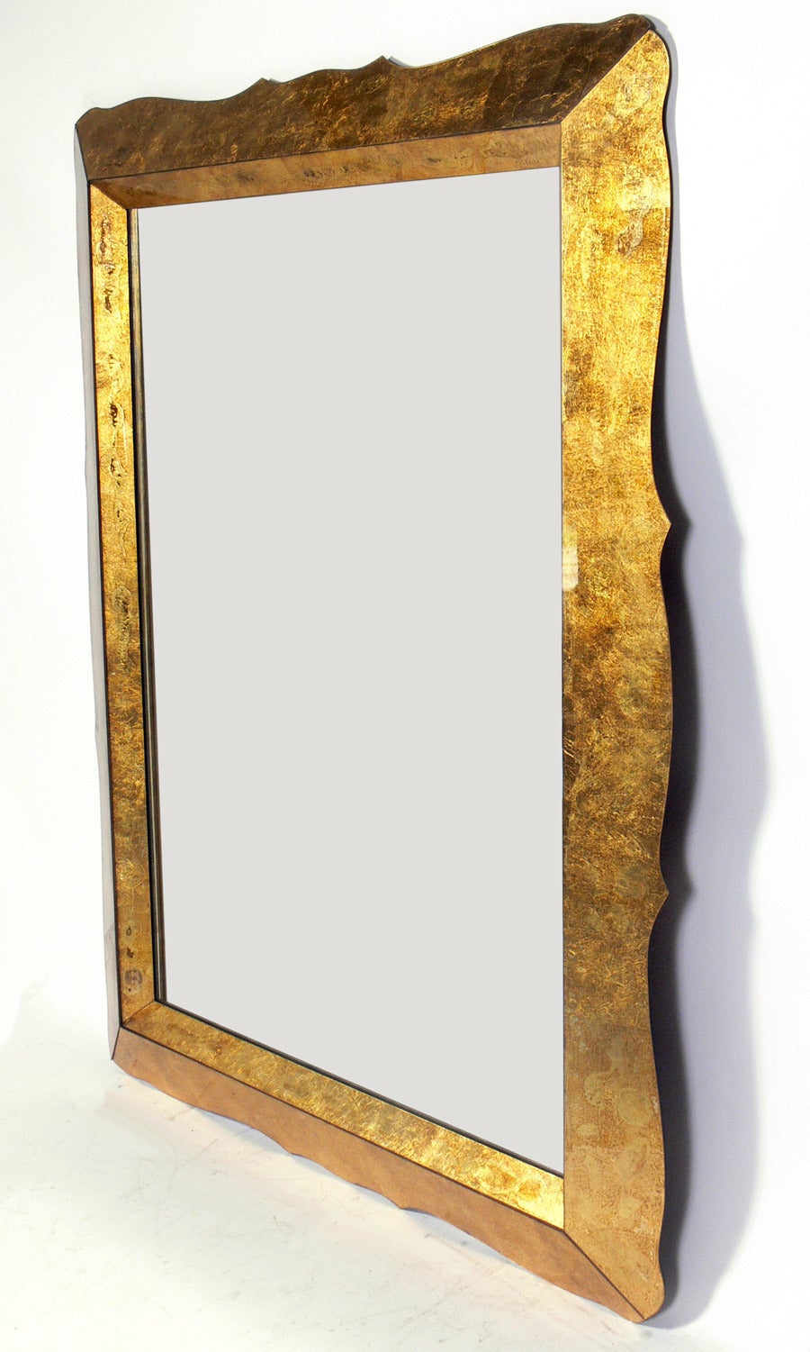 Large Scale Gold Leaf Églomisé Mirror, American, circa 1940s. Retains its wonderful original patina to the mirror and gilding. At just over five feet tall by just over four feet wide, this mirror exhibits large scale glamour. It can be mounted