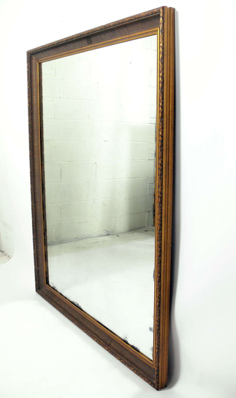Large Scale Antiqued Mirror, American, circa 1950's. Warm patina to both the mirrored glass and the gilt wood frame.
