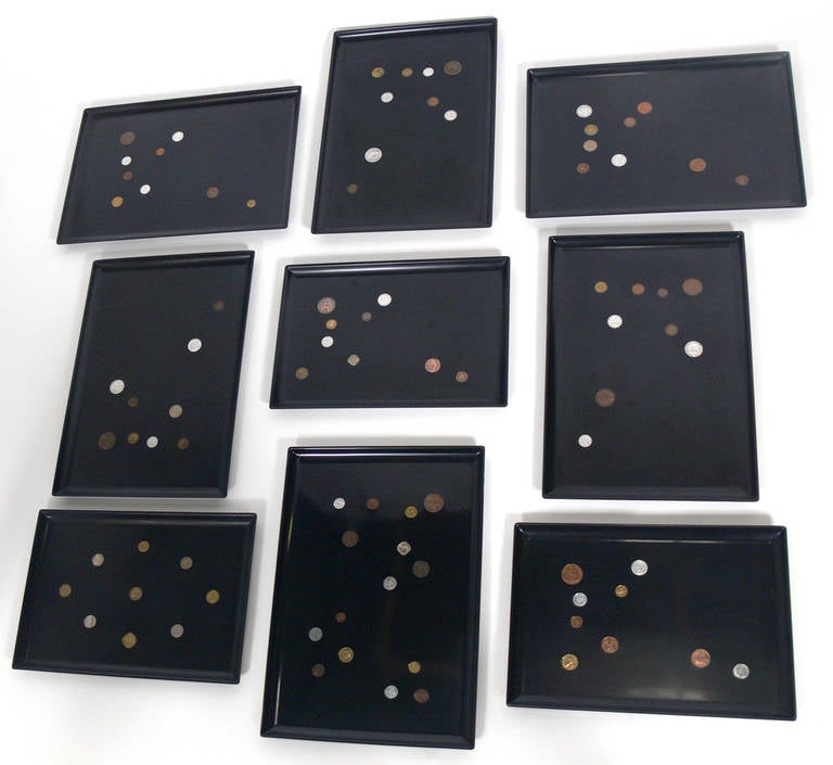 Group of nine coin inlaid trays by The Couroc Company, American, circa 1950s. These would look great mounted on a wall together. Constructed of antique coins mounted in black resin trays.