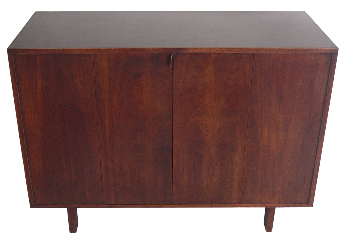 Custom Midcentury Walnut Credenza, handmade by George Cohen for his workshop, the Creative Woodwork Company of New York City, circa 1960s. It offers a voluminous amount of storage. The bifold doors open to reveal two adjustable shelves and one fixed