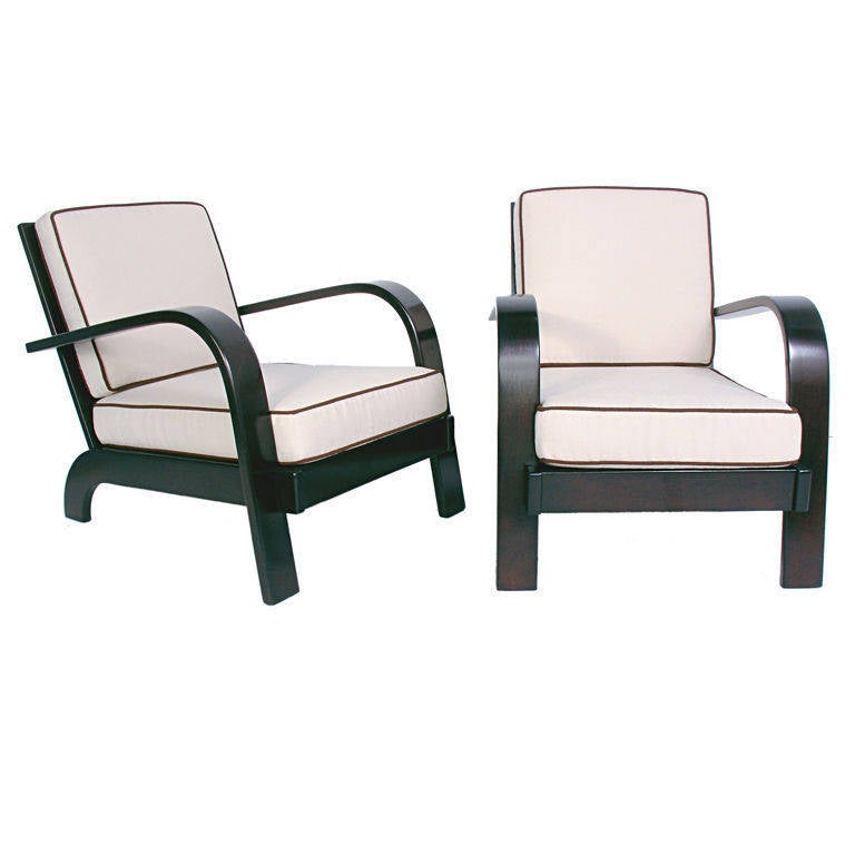 Pair of Streamlined Lounge Chairs, designed by Russel Wright for Conant Ball, circa 1940s. They have been refinished in an ultra-deep brown lacquer and reupholstered in an ivory color fabric with dark brown trim.