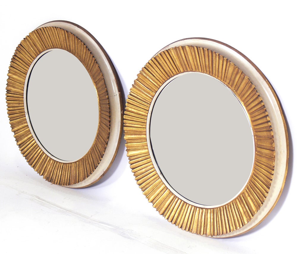 Pair of Elegant Gilt Sunburst Mirrors, probably French, at least circa 1940's, possibly earlier. They have a gilt sunburst facade with ivory color sides and gilt back trim. Wonderful original patina to both the mirrored glass and frames. They are