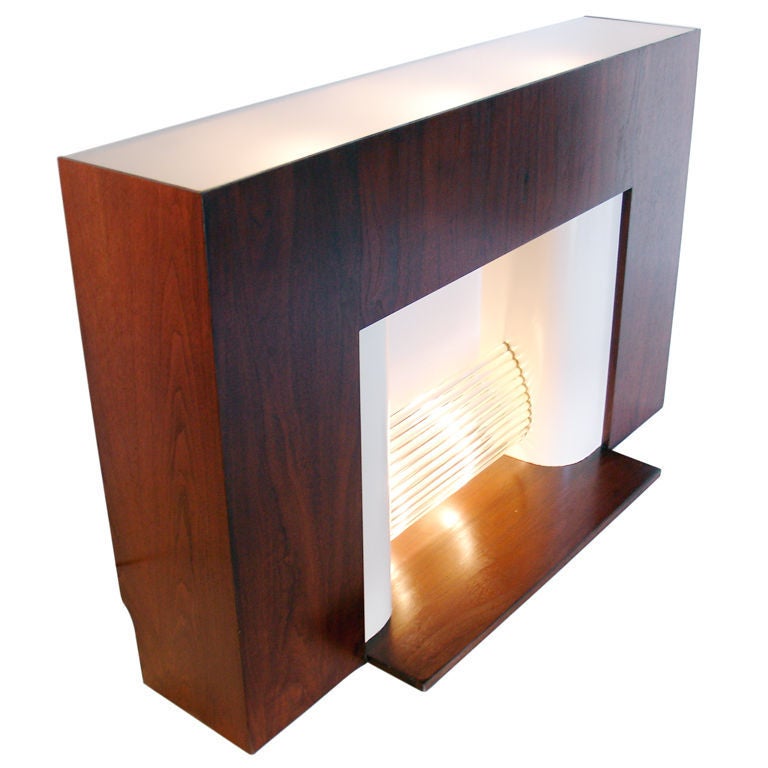 Art Deco Fireplace Mantle, circa 1930's. This fireplace needs no gas or other hookups. It has backlit glass rods to replace the fire. They look very glamorous when lit. It also features a backlit frosted glass top. It is executed in walnut and ivory