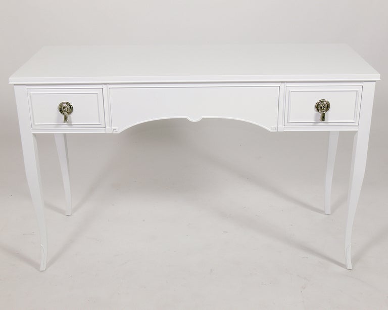 Elegant White Lacquer Desk with Nickel Hardware, American, circa 1940's. This piece has been completely restored in a white color lacquer with the nickel hardware replated. It has a deep drawer in the center, with two smaller deep drawers on either