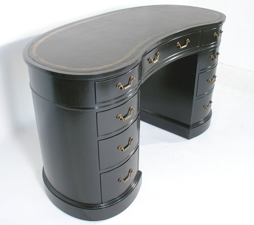 Black Lacquered Kidney Shaped Desk, American, circa 1950's. It has been refinished in sleek black lacquer, and retains it's original black color Greek Key embossed leather top. It offers a voluminous amount of storage in a small footprint, with nine