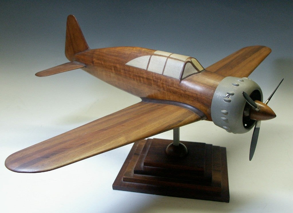 This is a an early World War II fighter airplane engineering test model. Beautifully carved from wood of a marquetry construction with a painted cockpit, aluminum cowling & propeller blades.  Mounted on a skyscraper styled wooden base with a center