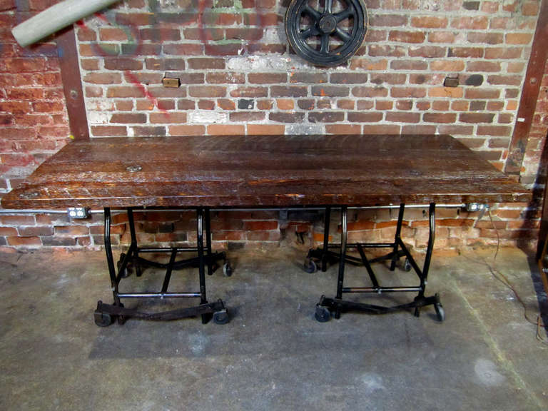 Finished, industrial table with original washers inset into top.  Adjustable, typewriter bases at either end.  Wheels can be set up or down.  Wheels down give an added inch of height to 31