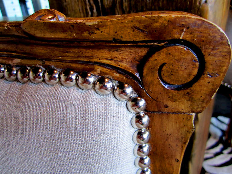 Newly upholstered chairs in French linen.  Beautiful, hand carved detail, and silver tack accents.